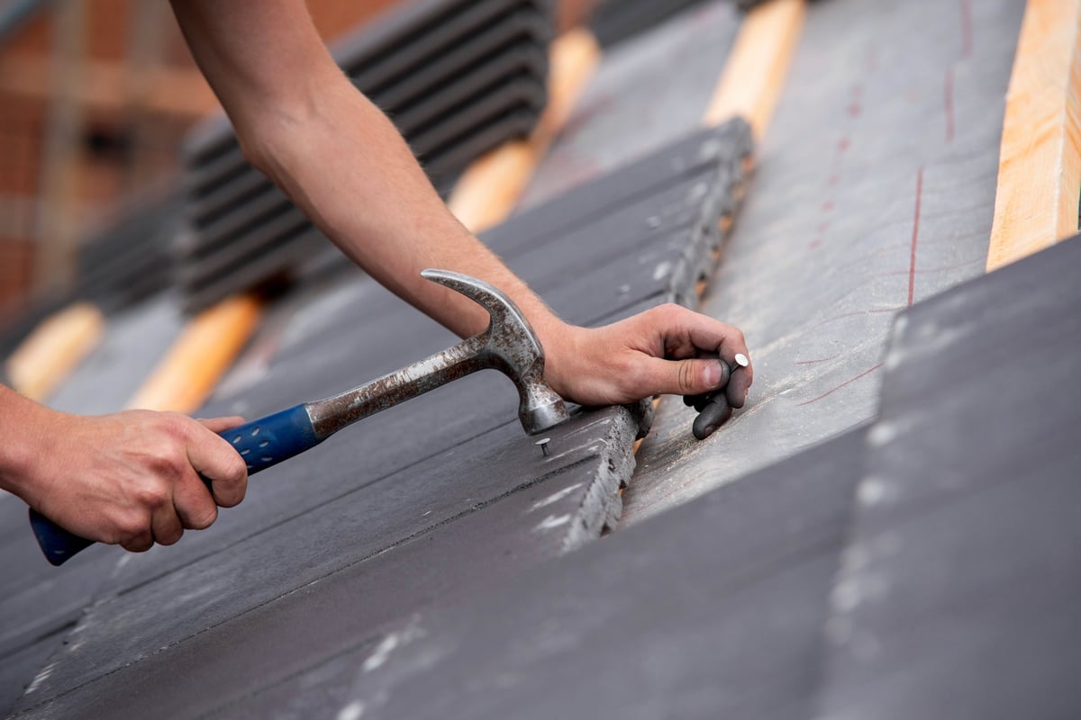 Close-up of roof tiles being laid and aligned by hand