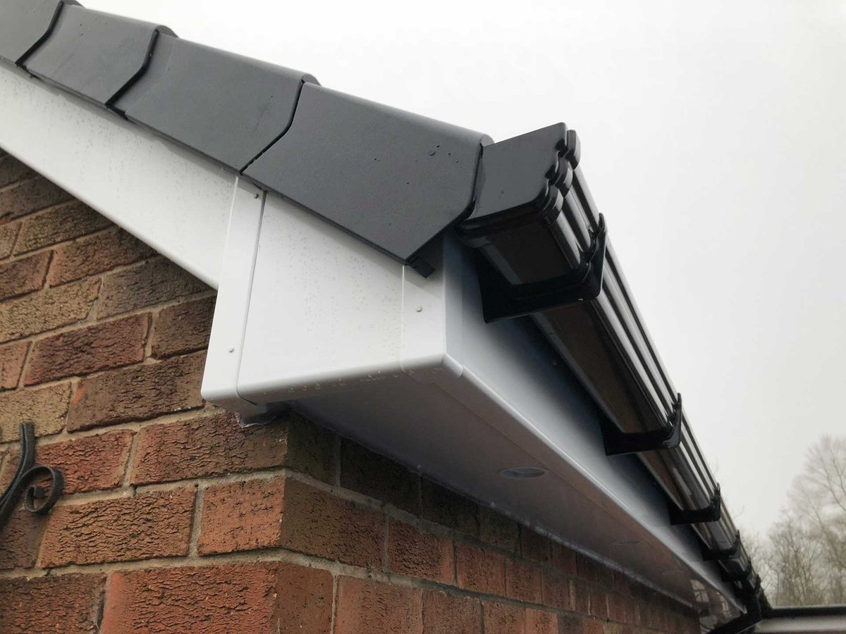 Close-up of new guttering and downpipe installed on a brick house with white soffit fascia