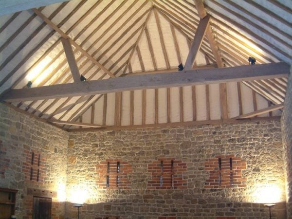 Interior of a stone building with exposed wooden roof beams — the underside of a finished warm roof